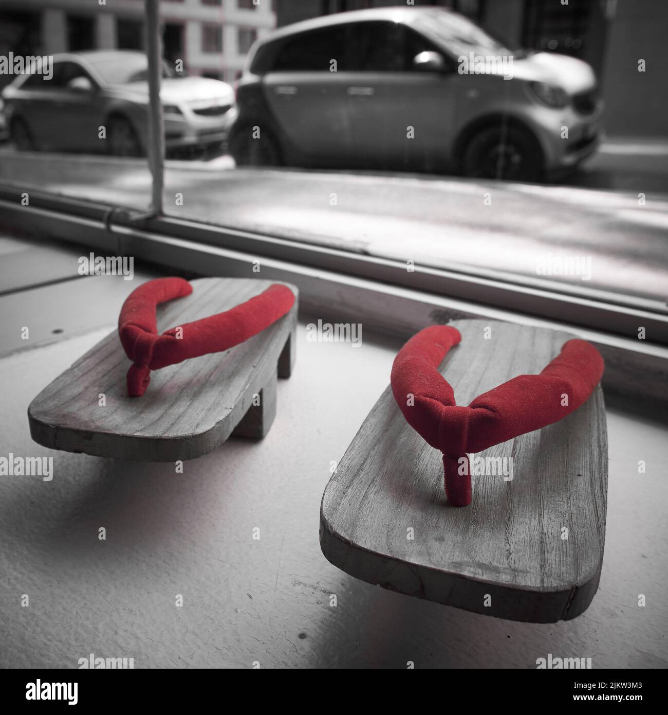 Una foto in scala di grigi di un paio di pantofole in legno con dettagli rossi Foto Stock