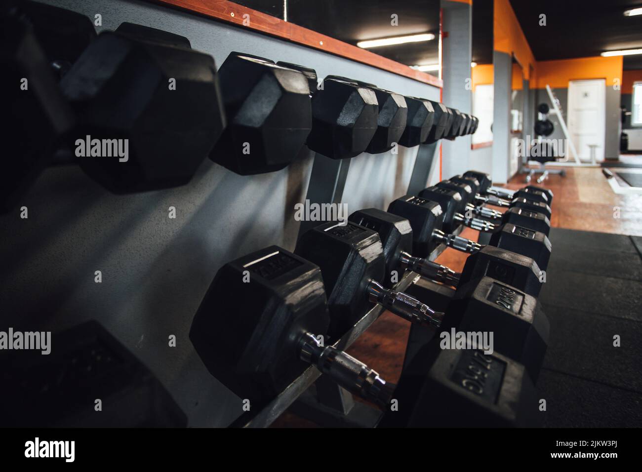 Un bel colpo di linee di manubri neri sugli scaffali in palestra body building Foto Stock