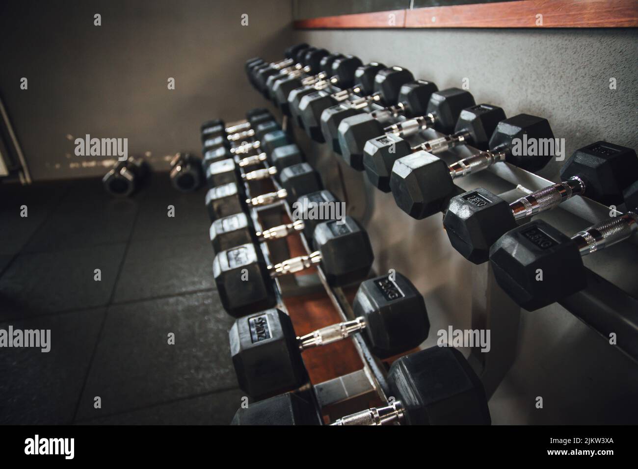 Un bel colpo di linee di manubri neri sugli scaffali in palestra body building Foto Stock