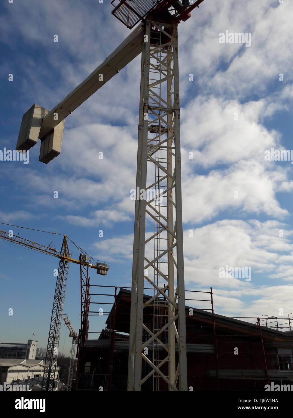 Un colpo verticale di gru a torre sul cantiere su un cielo nuvoloso blu sullo sfondo Foto Stock