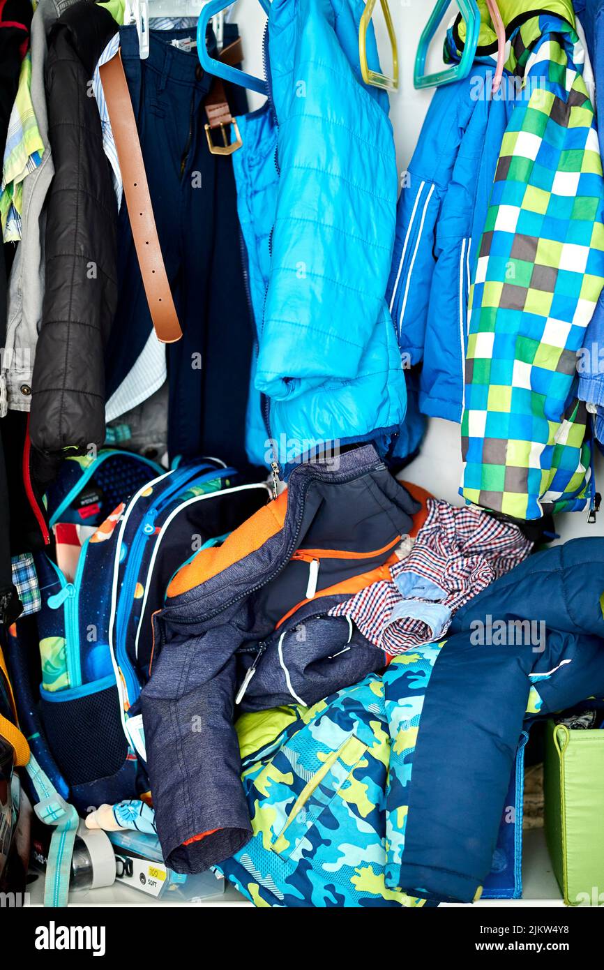 Un armadio aperto e disordinato con vestiti per bambini Foto Stock