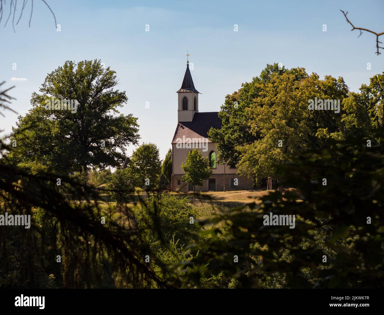 Chiesa edificio nel mezzo della natura. Alberi verdi e piante accanto alla casa di culto. Tradizionale architettura cristianica in Germania. Foto Stock