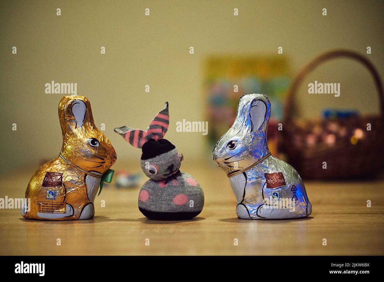 Due coniglietti pasquali al cioccolato Favorina e un coniglietto cucito su un tavolo Foto Stock