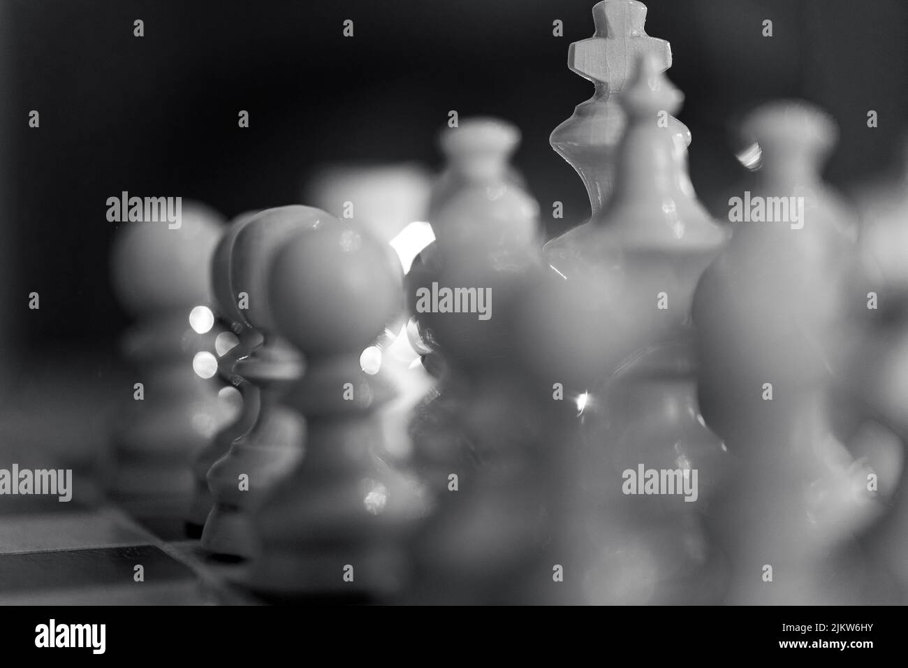 Un primo piano in scala di grigi dei pezzi di scacchi bianchi. Messa a fuoco selezionata. Foto Stock