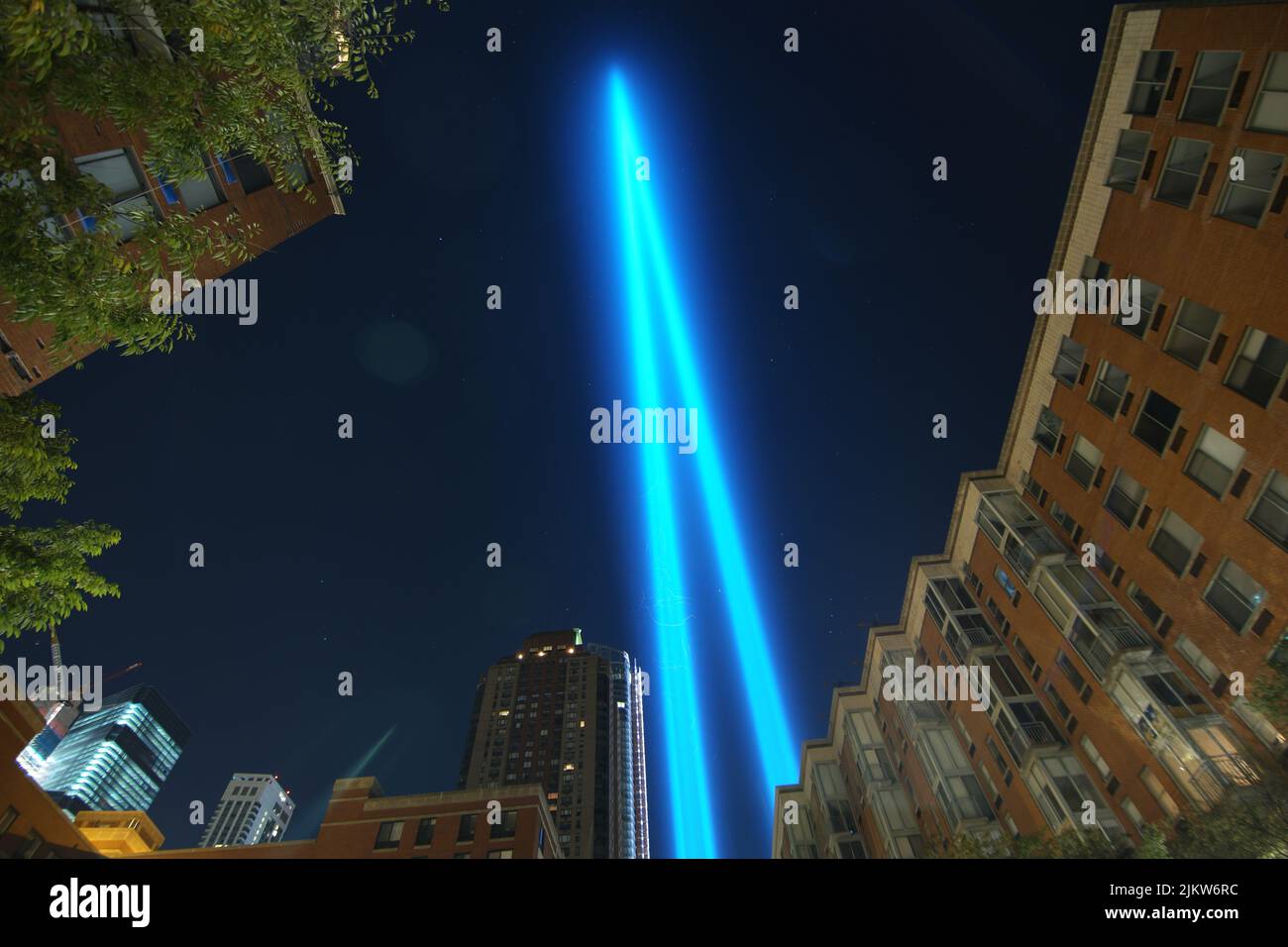 Una vista ad angolo basso degli edifici e delle luci blu del memoriale del 11th settembre a NYC di notte Foto Stock