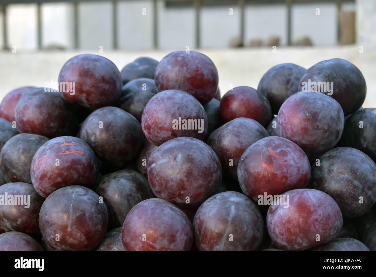 Mucchio di frutta fresca matura prugna rossa per la vendita al mercato locale, sfondo texture Foto Stock