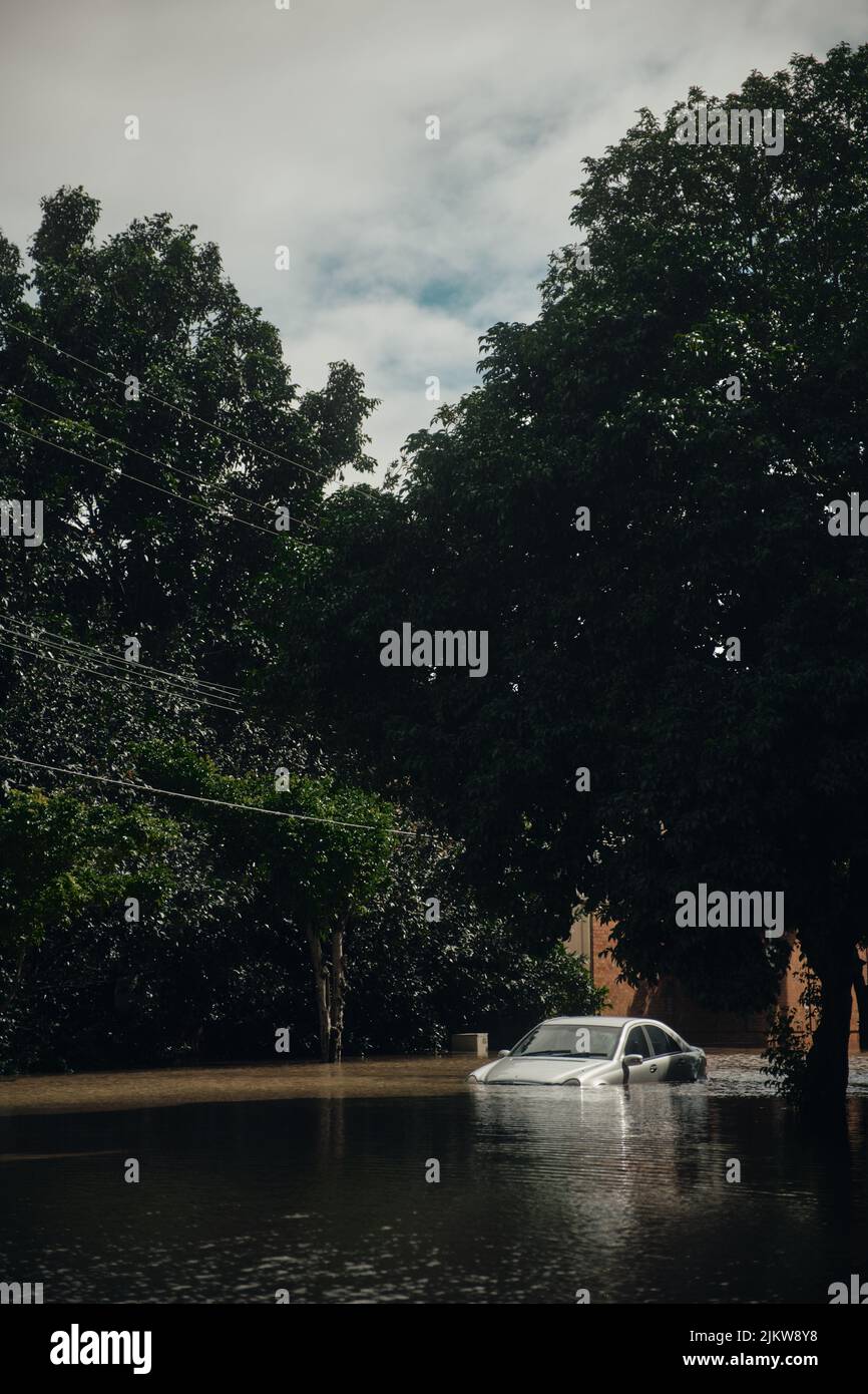 Un'auto di lusso argentata intrappolata nelle acque alluvionali durante un disastro naturale. Foto Stock