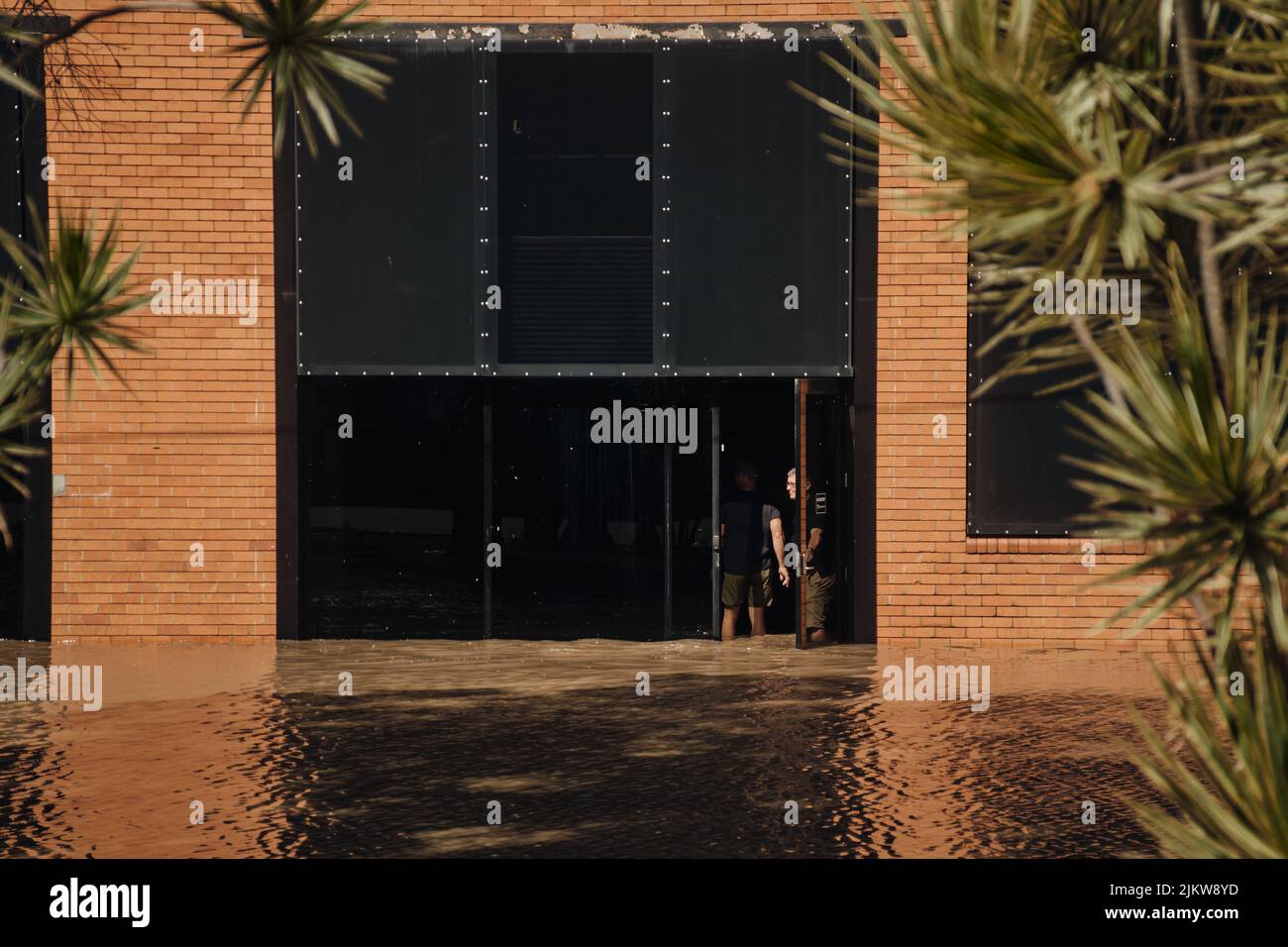 Due imprenditori locali entrano nel loro negozio per valutare i danni causati dalle inondazioni Foto Stock