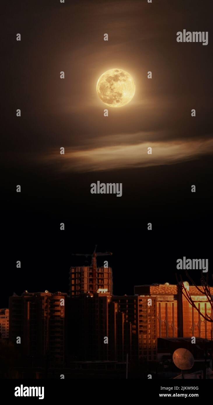 Una vista ipnotica di una luna nel cielo scuro di notte sopra una città Foto Stock