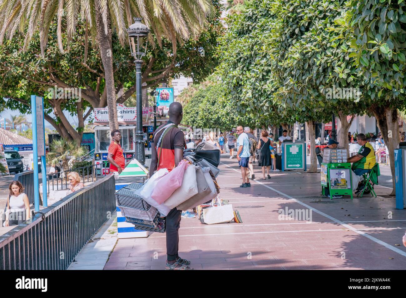 Un venditore di strada su strada con molti turisti sta vendendo i sacchetti contraffatti moda per le ragazze, i sacchetti popolari delle repliche dei marchi. MARBELLA, MALAGA/SPAGNA Foto Stock
