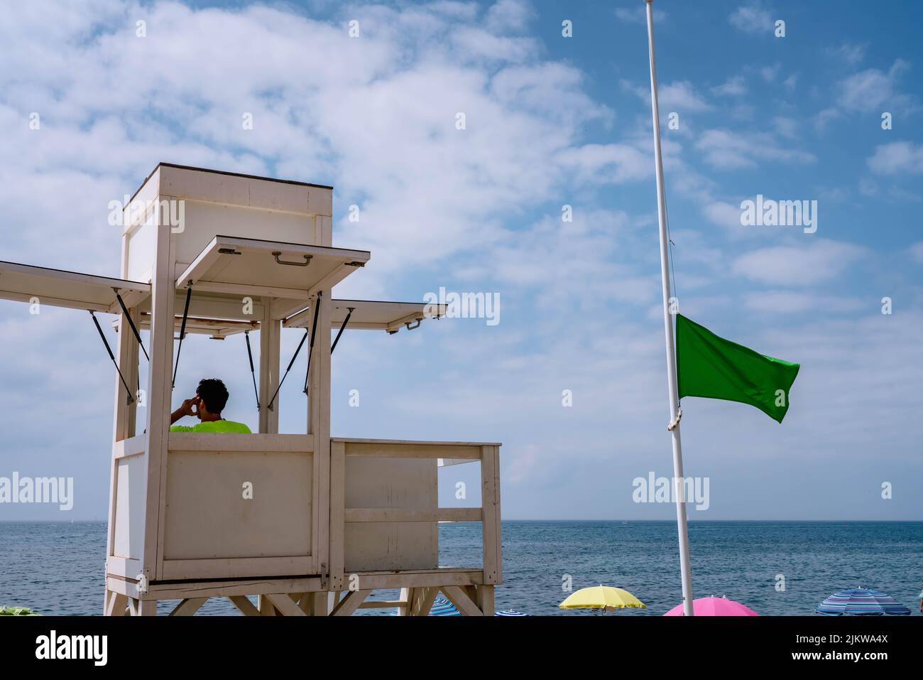 Guardia costiera di sicurezza presso la torre costiera di sicurezza, bandiera verde che indica le condizioni di sicurezza per i visitatori della spiaggia Foto Stock