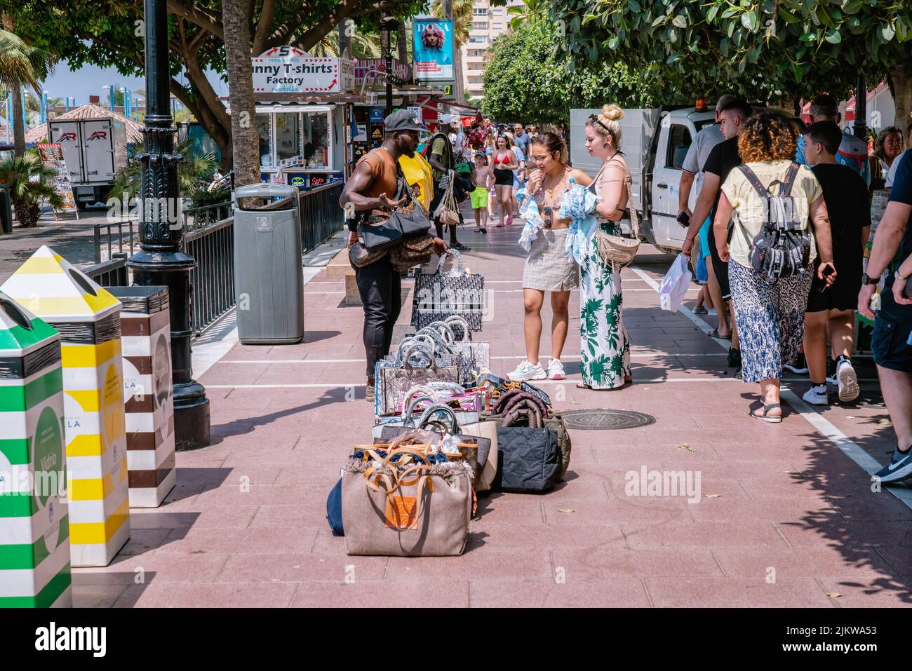 Un venditore di strada su strada con molti turisti sta vendendo i sacchetti contraffatti moda per le ragazze, i sacchetti popolari delle repliche dei marchi. MARBELLA, MALAGA/SPAGNA Foto Stock