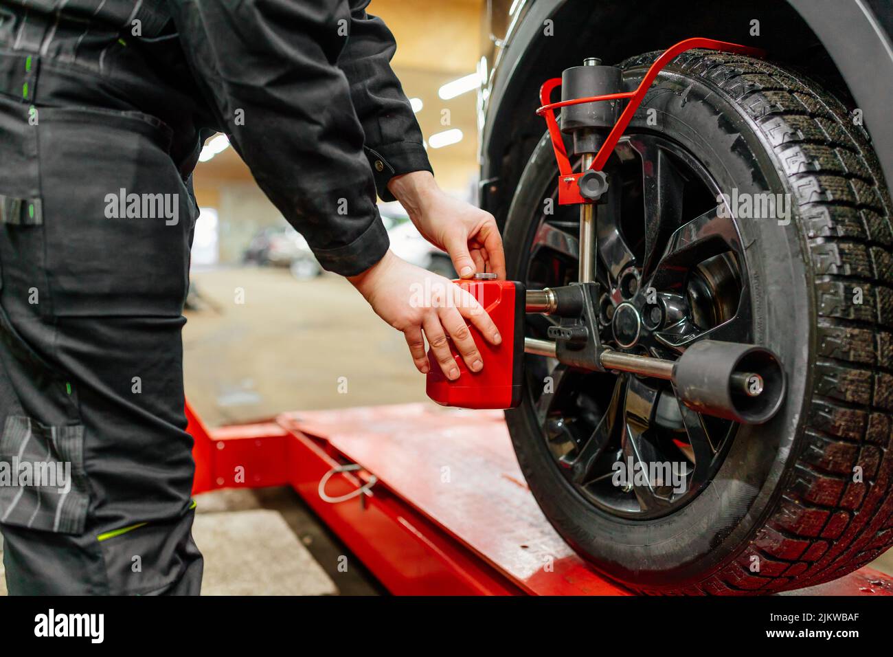 Il meccanico dell'auto installa i sensori di allineamento delle ruote, la regolazione delle sospensioni dell'auto. Meccanico al lavoro Foto Stock