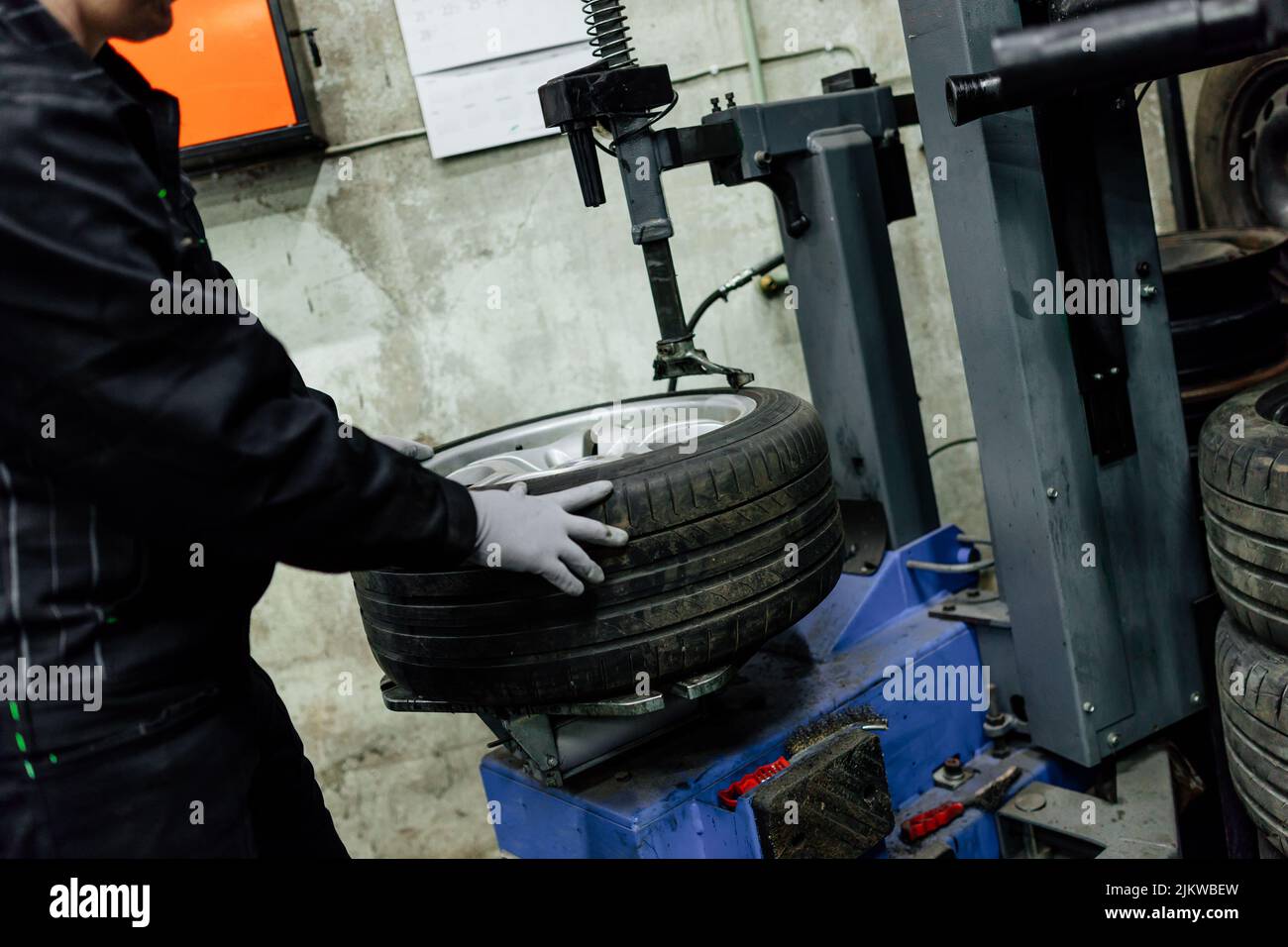 Meccanico auto che lavora alla riparazione del pneumatico della ruota del veicolo, sostituzione pneumatici estate. Foto Stock