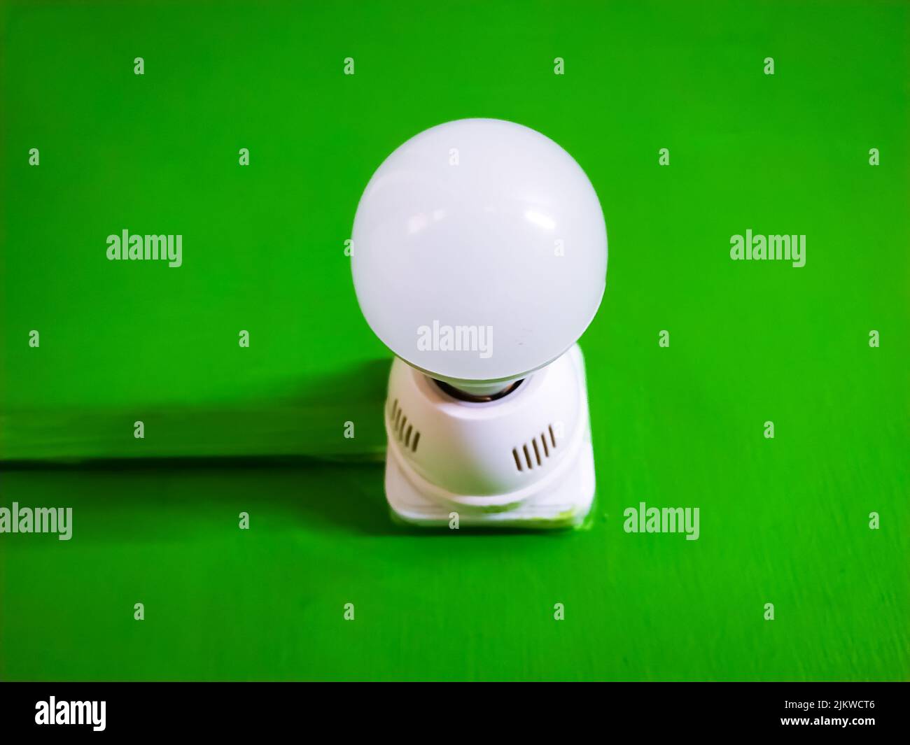 Un primo piano di una lampadina con un portalampada in plastica bianca isolato su sfondo cromato verde Foto Stock
