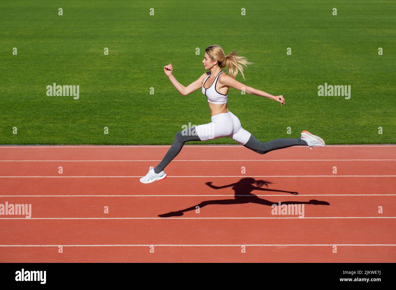 Donna che corre durante. Sfondi sportivi. Corridore. Sportivo professionista durante la sessione di allenamento. Donna che corre salta sul tracciato dello stadio Foto Stock