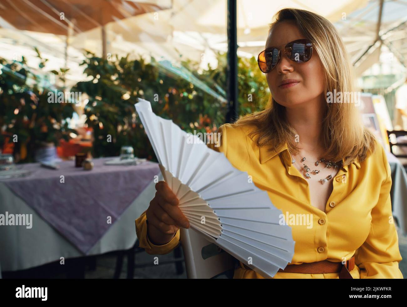 Donna con ventola portatile in climi caldi. Foto Stock
