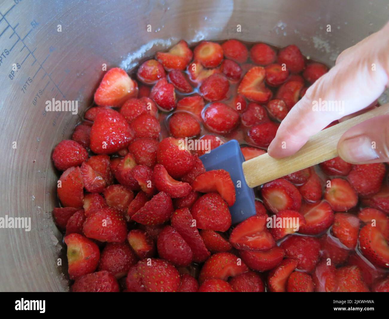 Gusto d'estate: Dopo aver seminato per una notte con zucchero, queste fragole vengono mescolate delicatamente prima di bollire rapidamente per fare la marmellata di fragole. Foto Stock