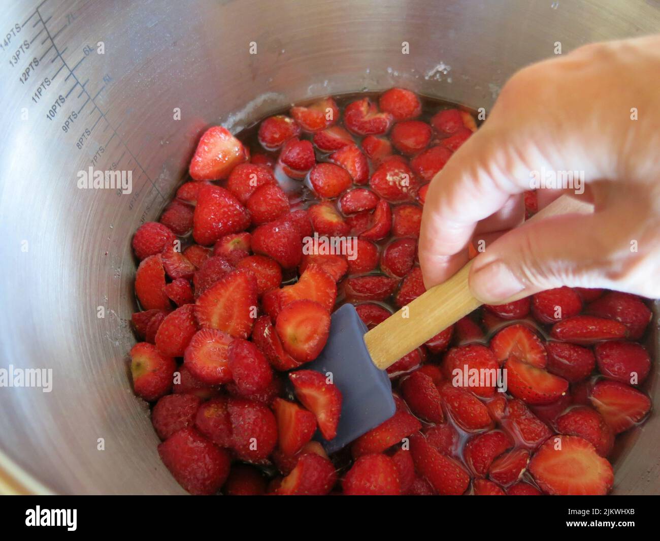 Gusto d'estate: Dopo aver seminato per una notte con zucchero, queste fragole vengono mescolate delicatamente prima di bollire rapidamente per fare la marmellata di fragole. Foto Stock