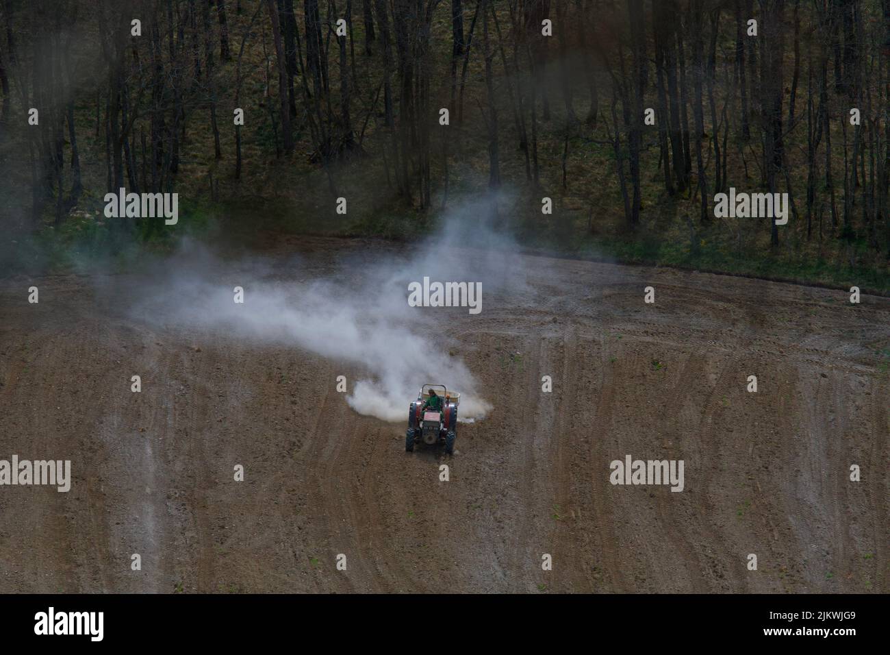 Il contadino irrorando il suo campo con una sostanza chimica bianca utilizzando un trattore. Inquinatore della natura. Foto Stock