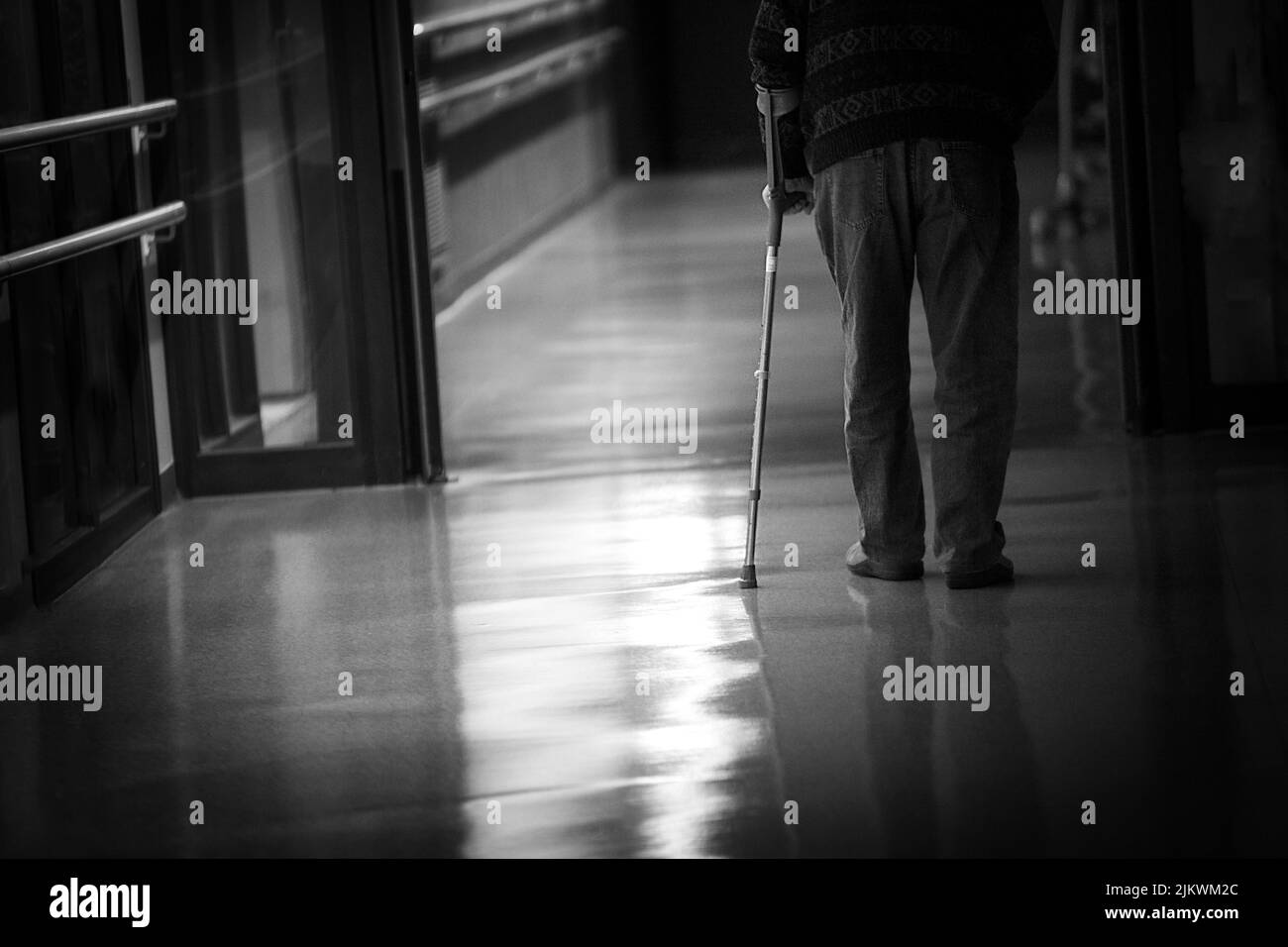Uomo con un bastone che cammina in un corridoio di una casa di riposo. Foto Stock