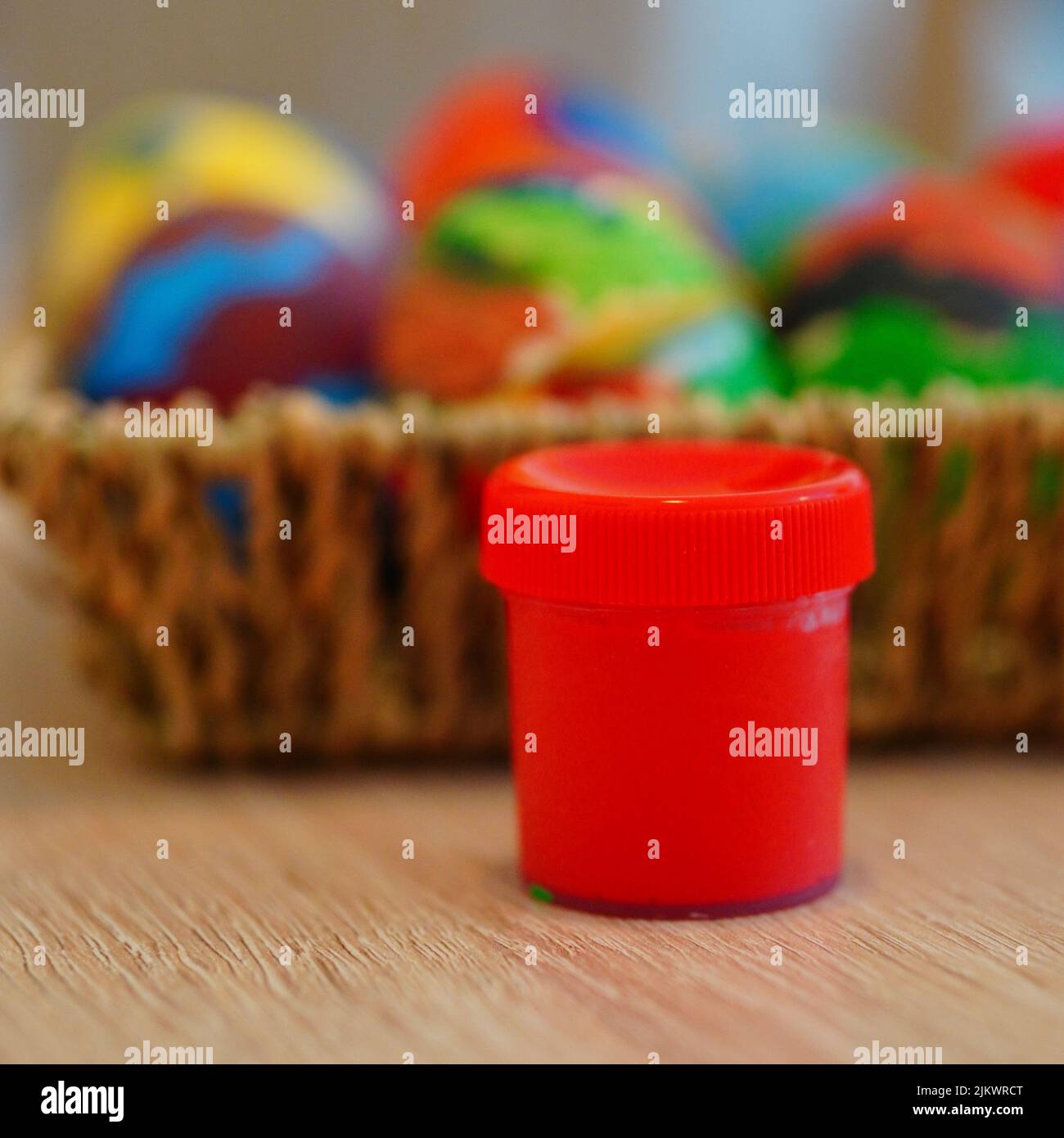 Un focus selettivo sparato di una vernice rossa presso il cesto di paglia con le uova colorate di Pasqua Foto Stock