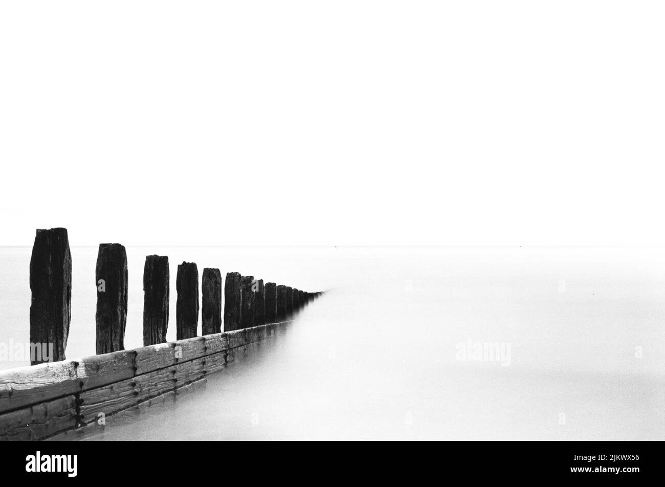 Una foto in scala di grigi di onde infrangenti sul mare con una lunga esposizione a Littlehampton Foto Stock