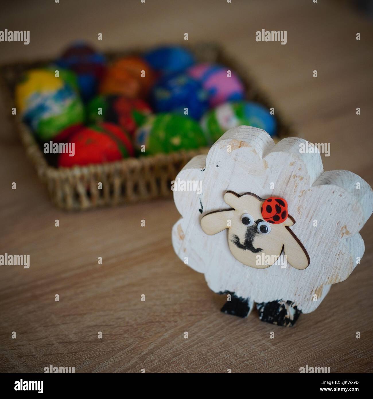 Una decorazione pasquale fatta a mano su un tavolo con un cesto di uova colorate Foto Stock