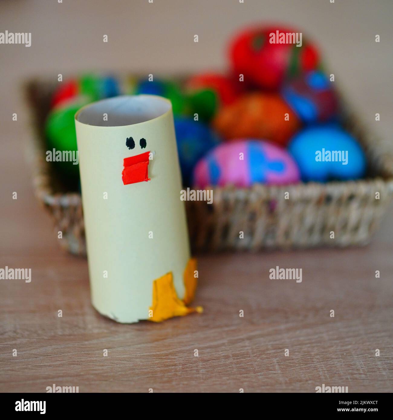 Un carciera di carta di fronte ad un cesto di uova di Pasqua su un tavolo Foto Stock
