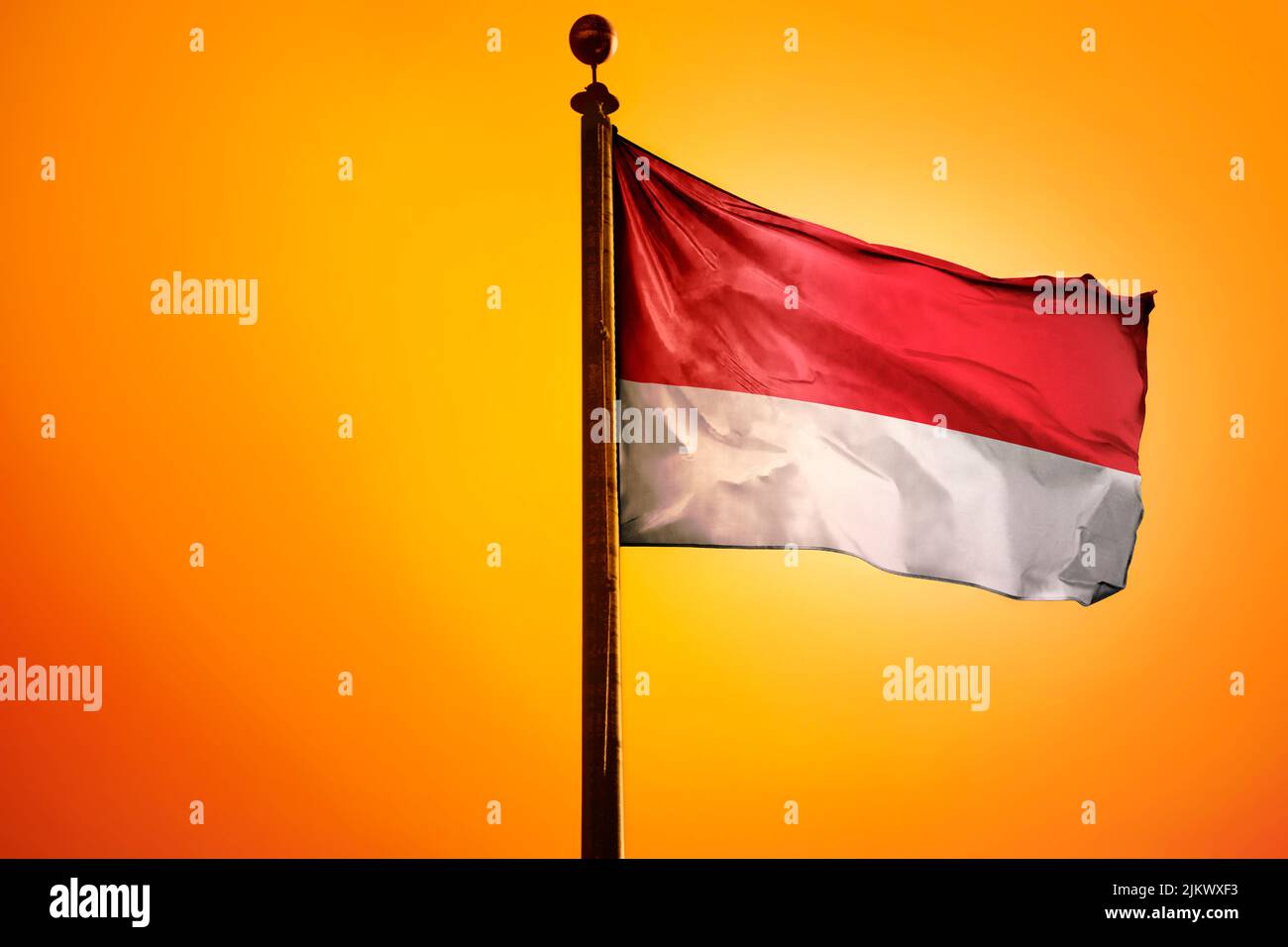 La bandiera nazionale dell'Indonesia su un flagpole isolato su uno sfondo arancione Foto Stock