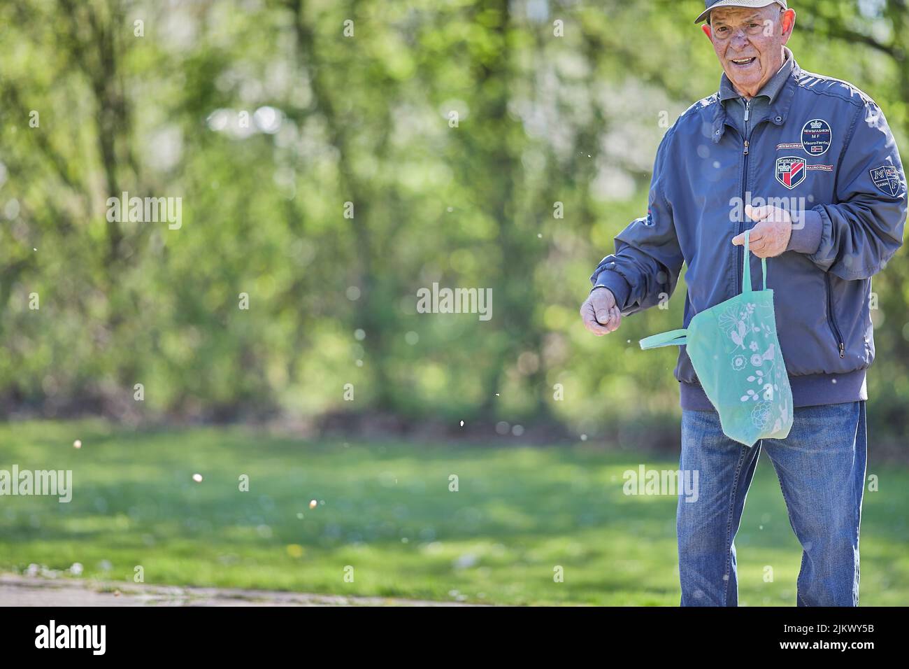 Un bellissimo scatto di un vecchio caucasico che alimenta le anatre nel parco in una bella giornata di sole a Geilenkirchen, in Germania Foto Stock