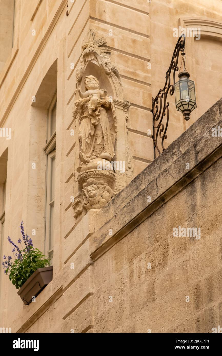 Avignone, una statua della Vergine Maria sulla facciata di una casa in una strada tipica, con edifici colorati Foto Stock