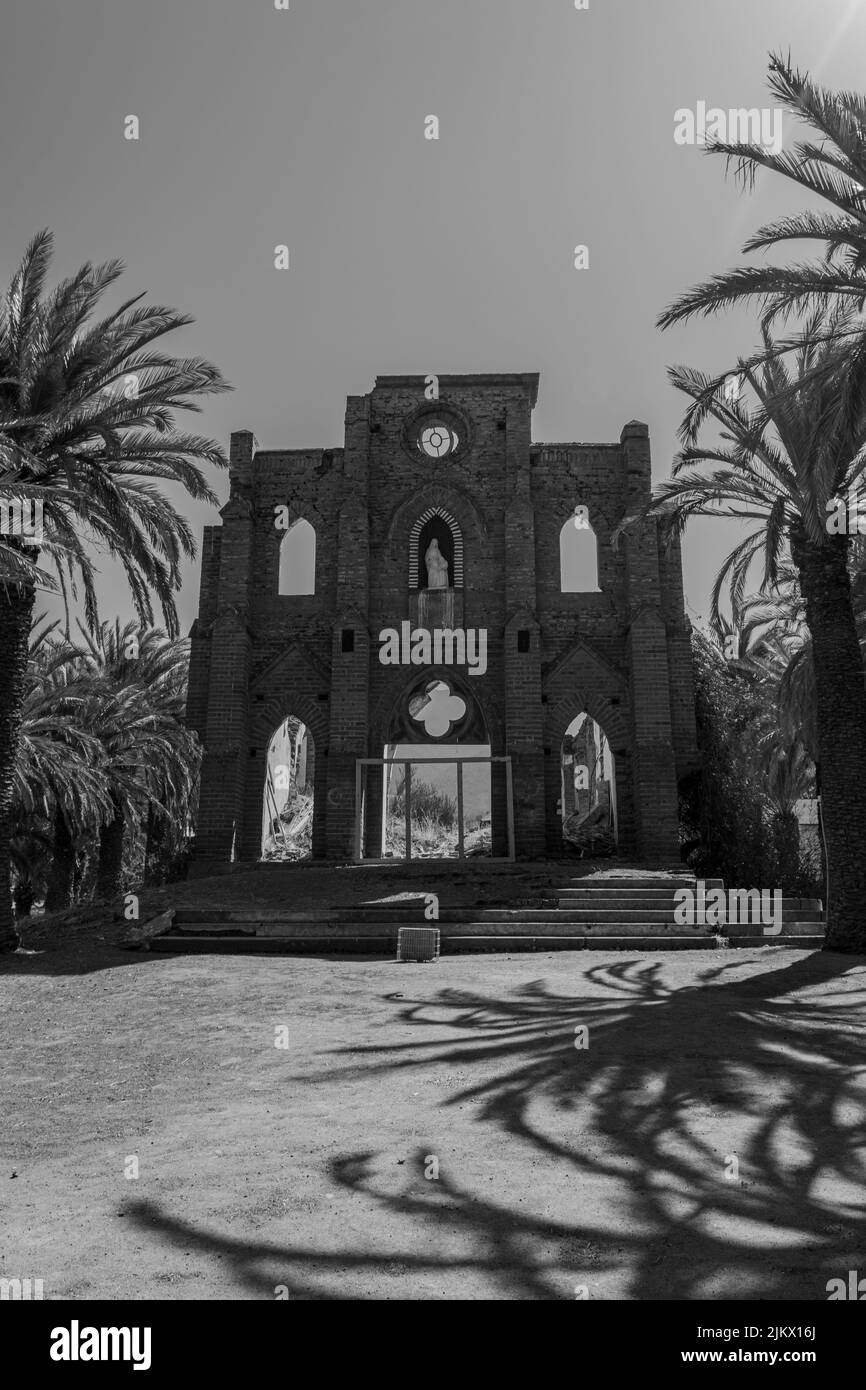 Uno scatto verticale dell'ingresso della chiesa circondato da palme nel comune di la Ligua in bianco e nero Foto Stock