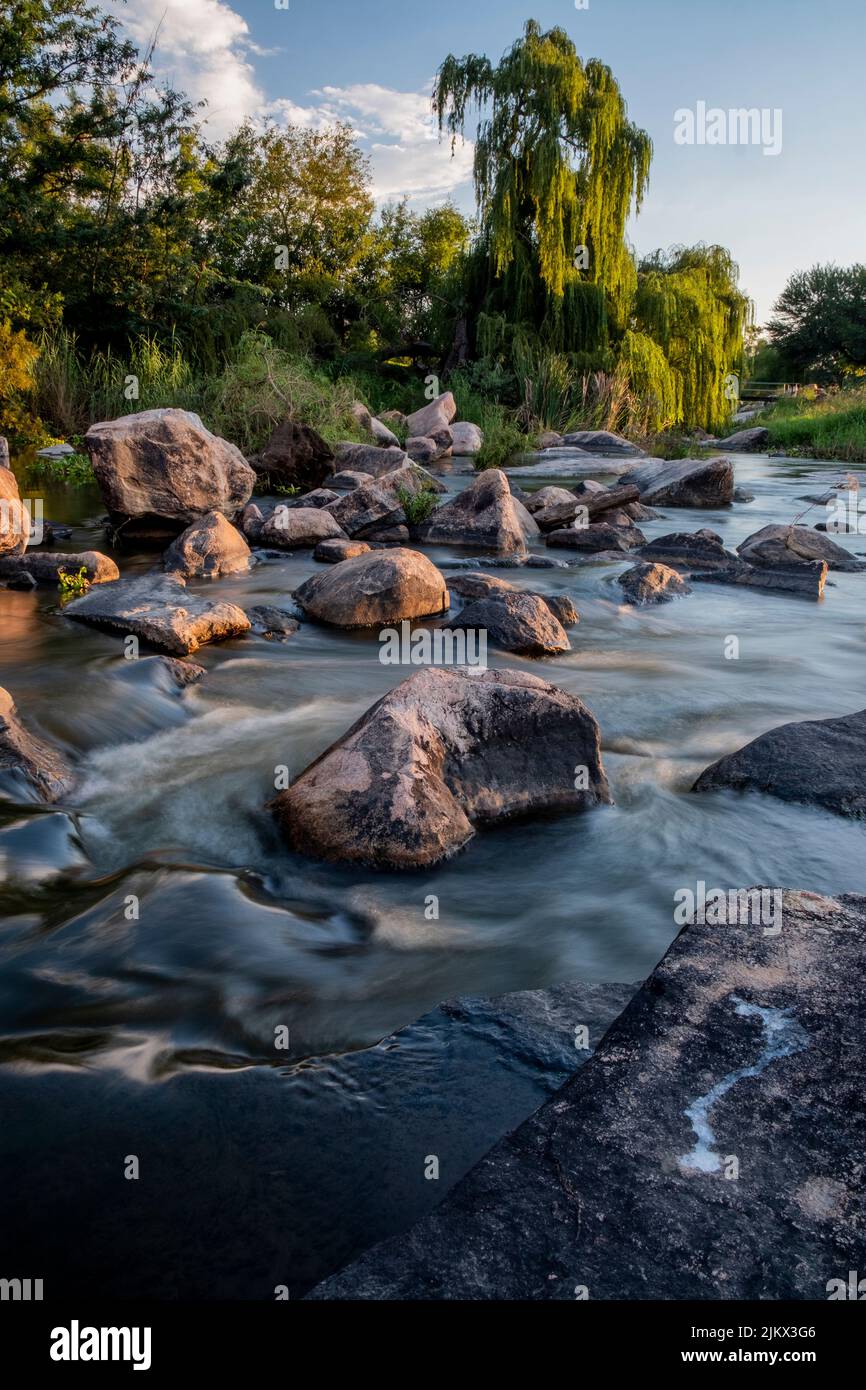 Uno scatto verticale di un fiume che scorre attraverso le rocce nel campo simile a un paradiso Foto Stock