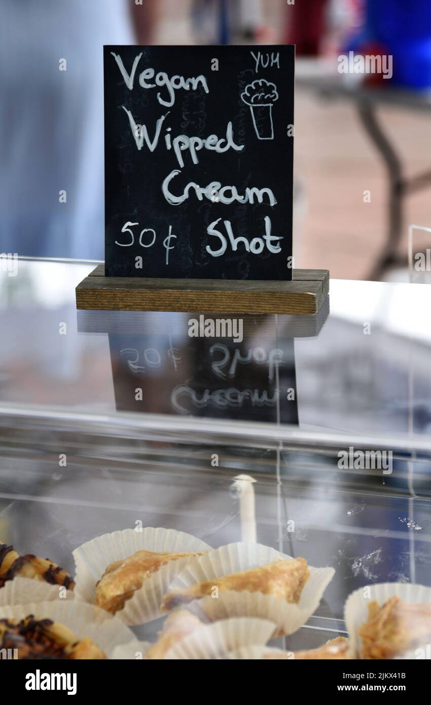 Un fornitore di cibo offre vegan panna montata shot sui suoi dessert al forno in un festival a Santa Fe, New Mexico. Foto Stock