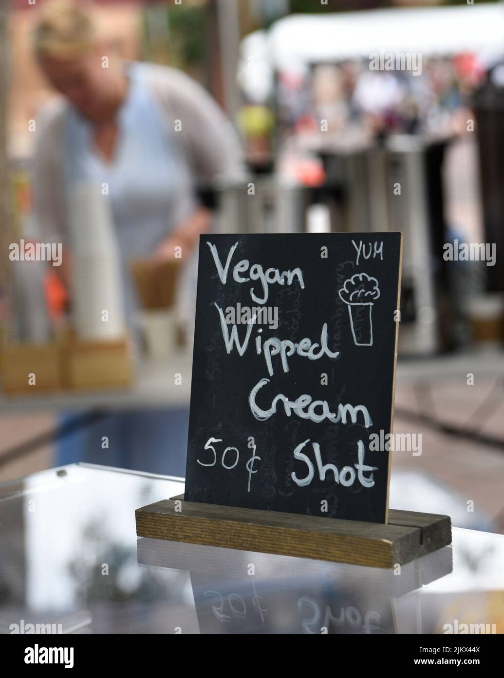 Un fornitore di cibo offre vegan panna montata shot sui suoi dessert al forno in un festival a Santa Fe, New Mexico. Foto Stock