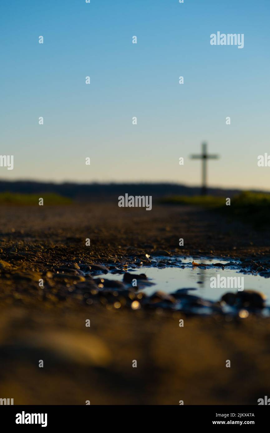 Un colpo verticale di una pozza e di una croce cristiana lontano sullo sfondo Foto Stock