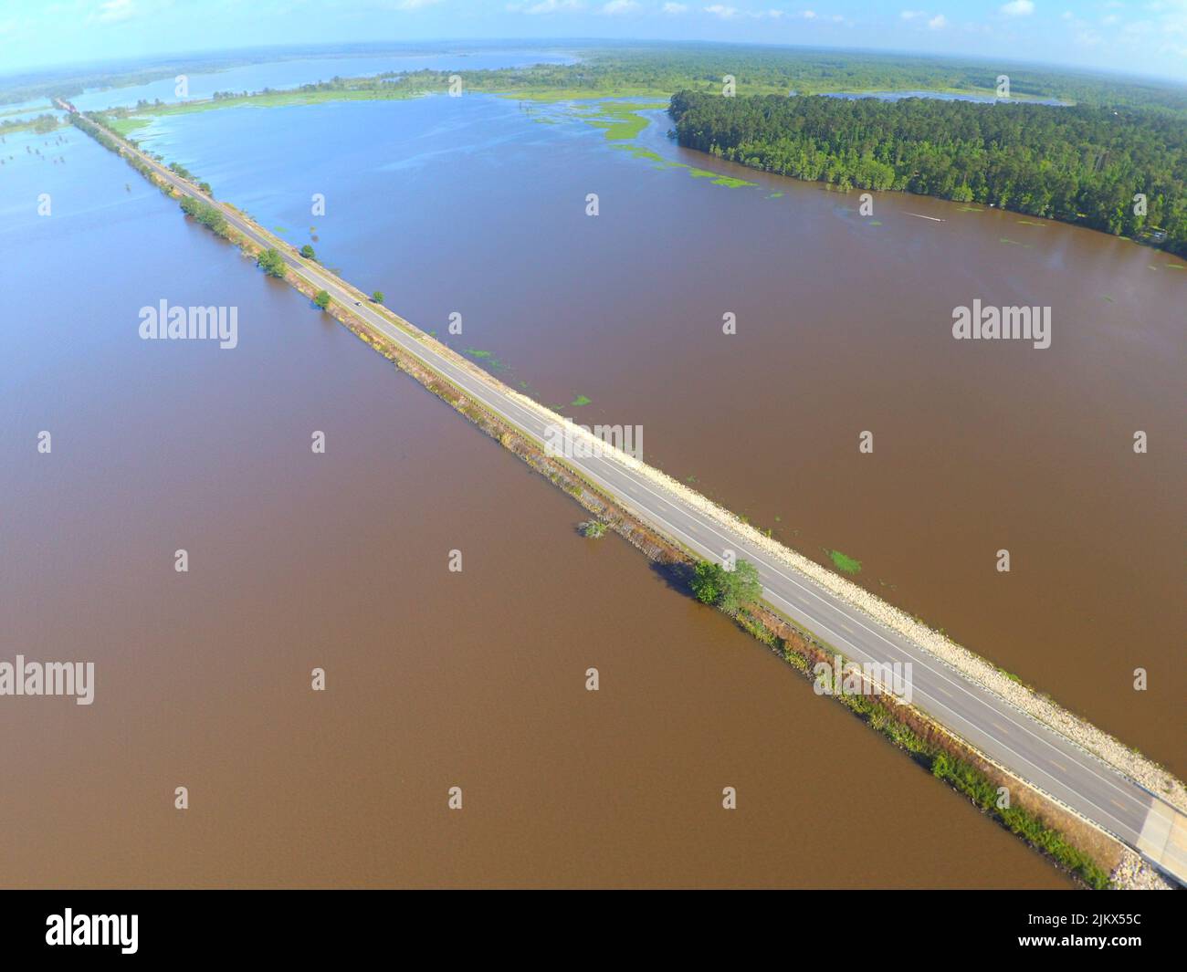 Una vista dall'alto di un'isola su strada asfaltata circondata da laghi che lavano le rive ricoperte di verde Foto Stock