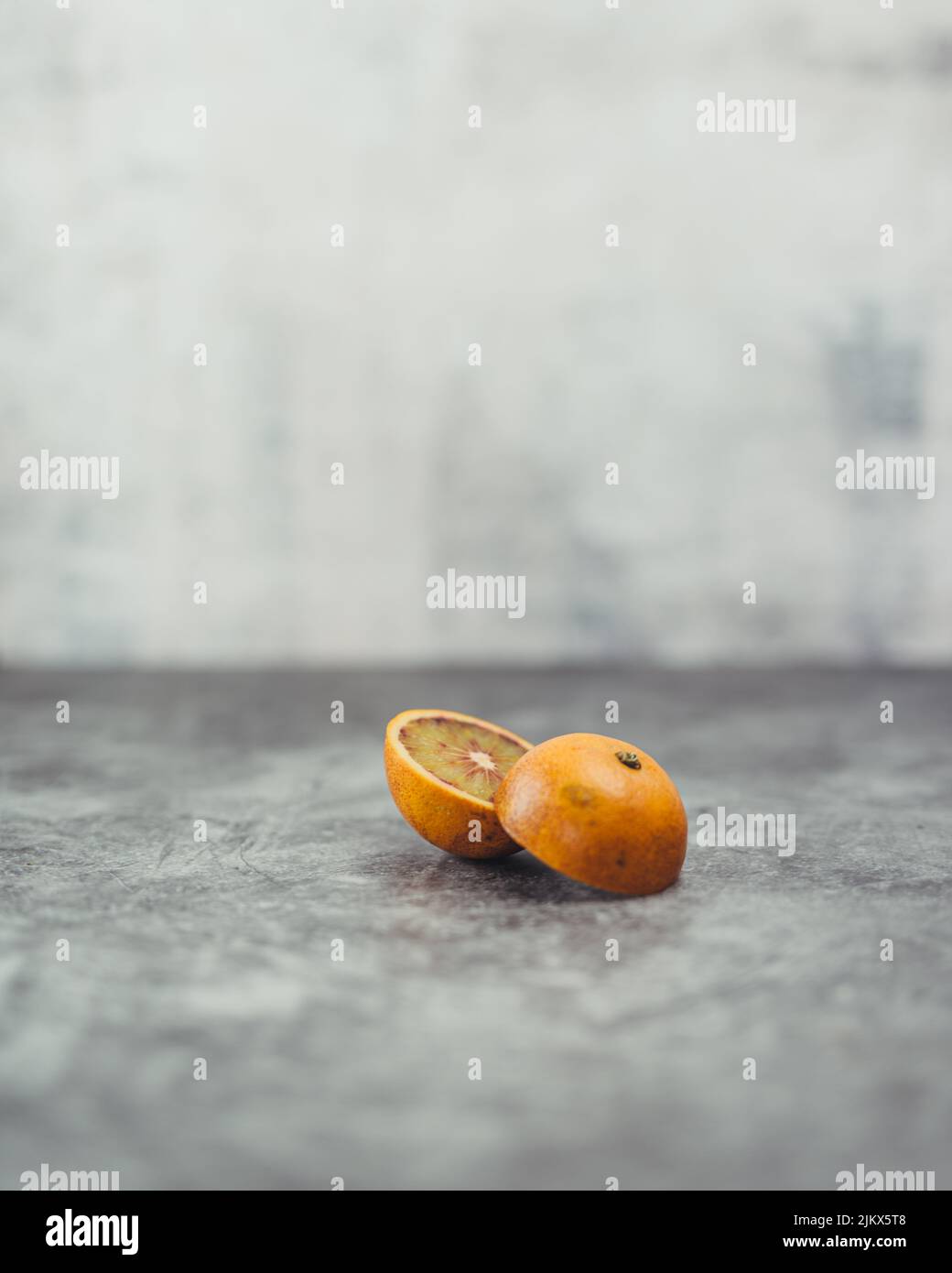 Un primo piano verticale dell'arancio affettato sulla superficie testurizzata grigia. Foto Stock