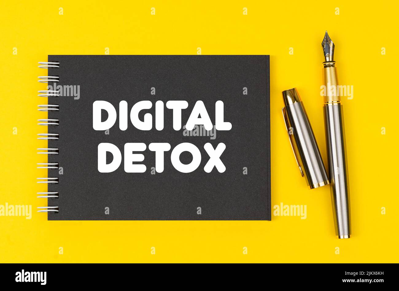 Concetto di business e finanza. Su uno sfondo giallo si trova una penna e un notebook nero con l'iscrizione - Digital Detox Foto Stock