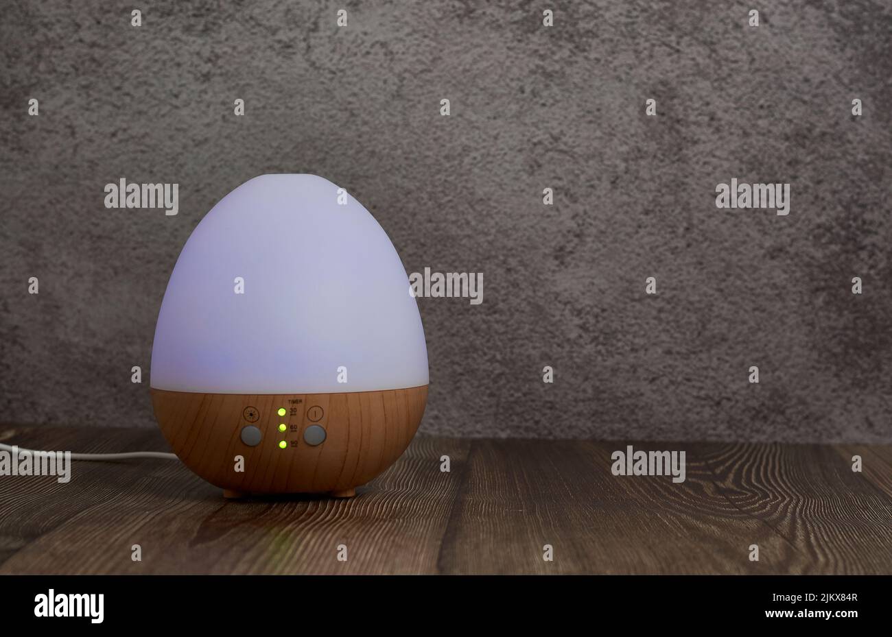 Un umidificatore a forma di uovo sul tavolo di legno contro una parete Foto Stock