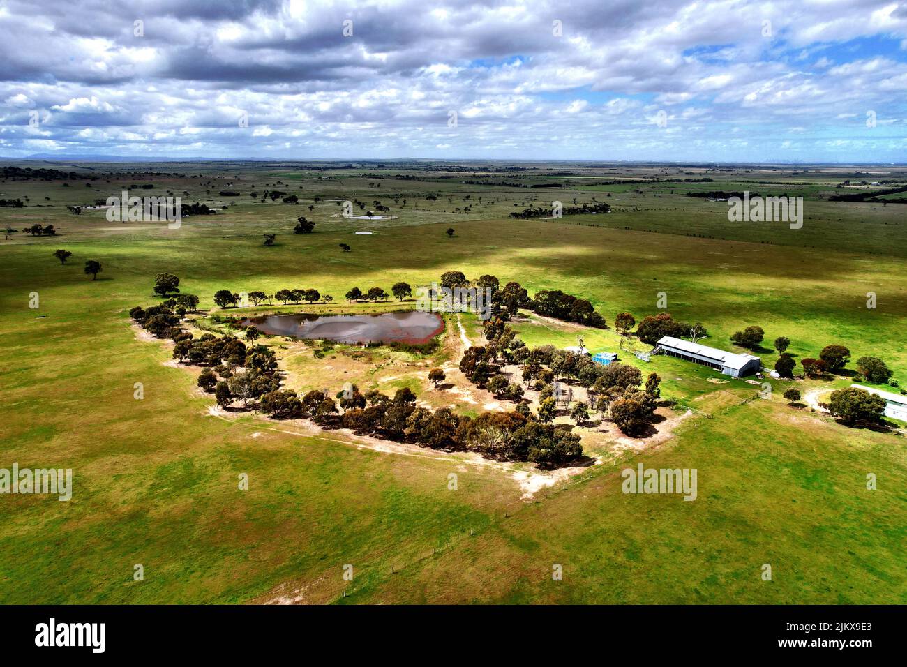 Una vista mozzafiato dei campi con alberi sparsi, edifici e un laghetto Foto Stock