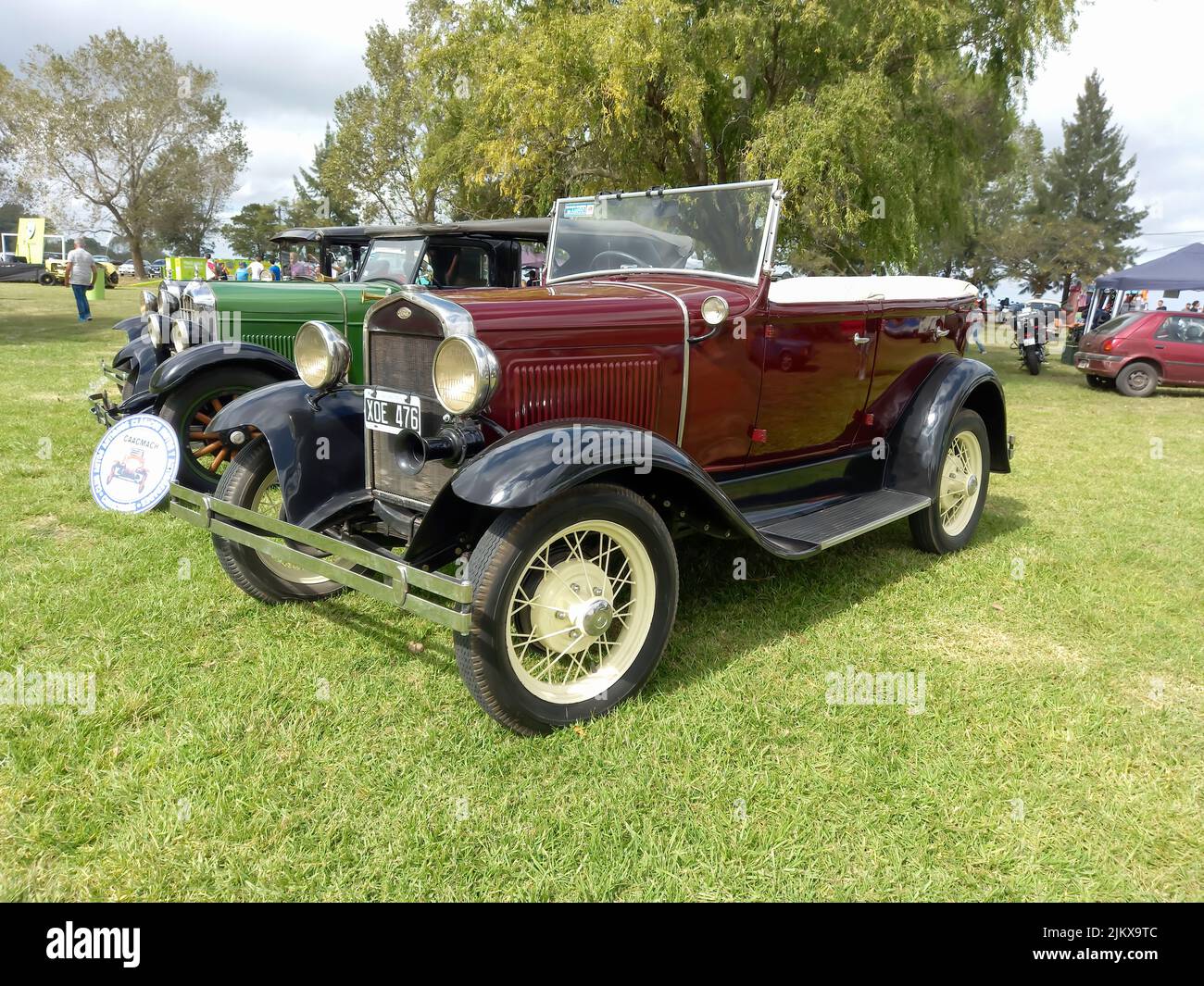 Chascomus, Argentina - Apr 9, 2022: Vecchio maroon rosso Ford modello B 1932 quattro porte convertibile. Vista laterale. Natura verde erba e gli alberi sfondo. Classico Foto Stock