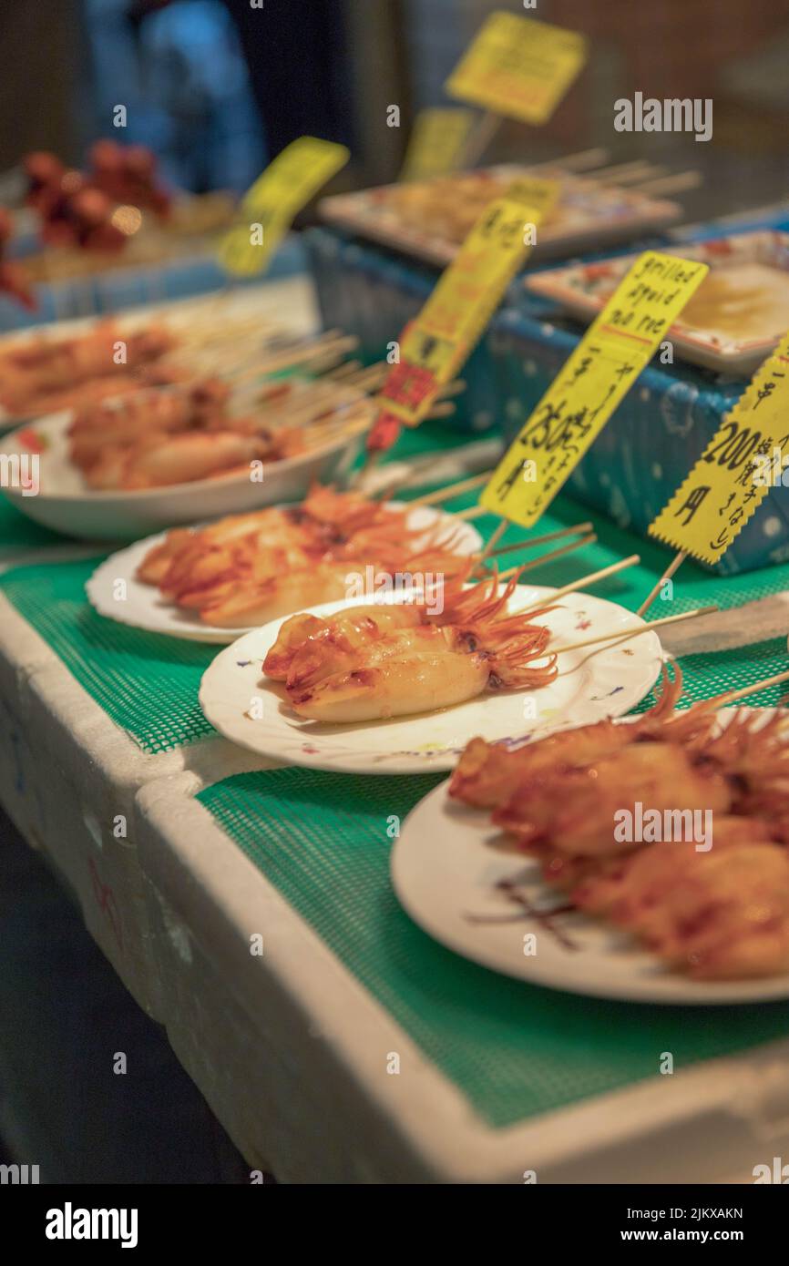 Uno shot verticale di calamari alla griglia in un mercato di cibo di strada Foto Stock