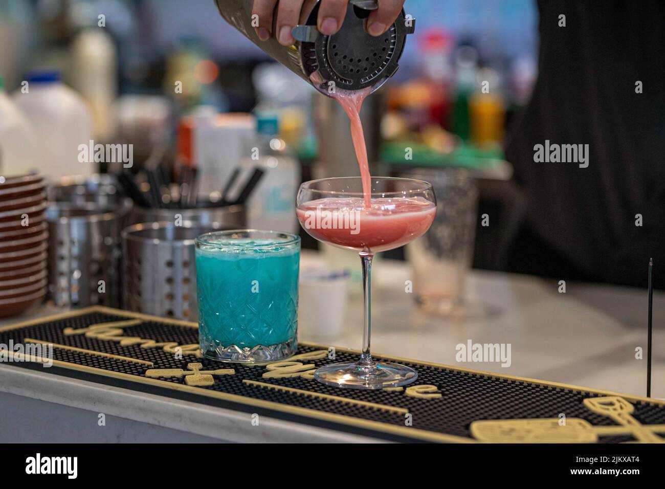 Un primo piano di un barman che versa un cocktail in un bicchiere Foto Stock