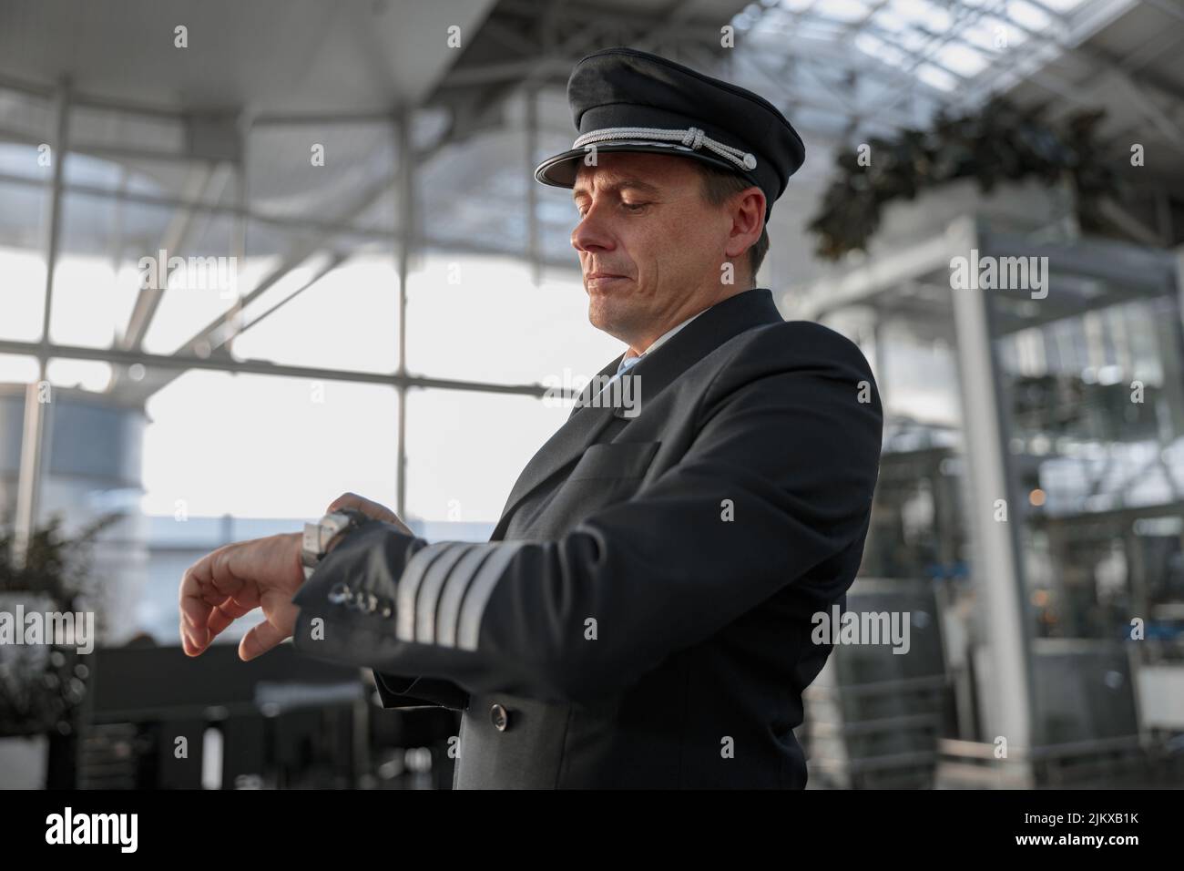 Pilota maschile che guarda l'orologio nel terminal dell'aeroporto Foto Stock