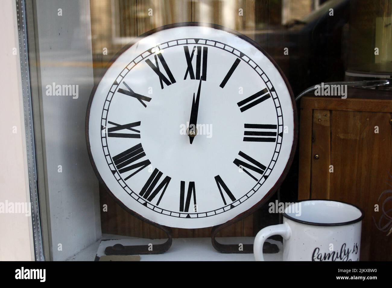 Un vecchio orologio bianco nella vetrina del negozio di antiquariato con una tazza a Langley, BC, Canada Foto Stock