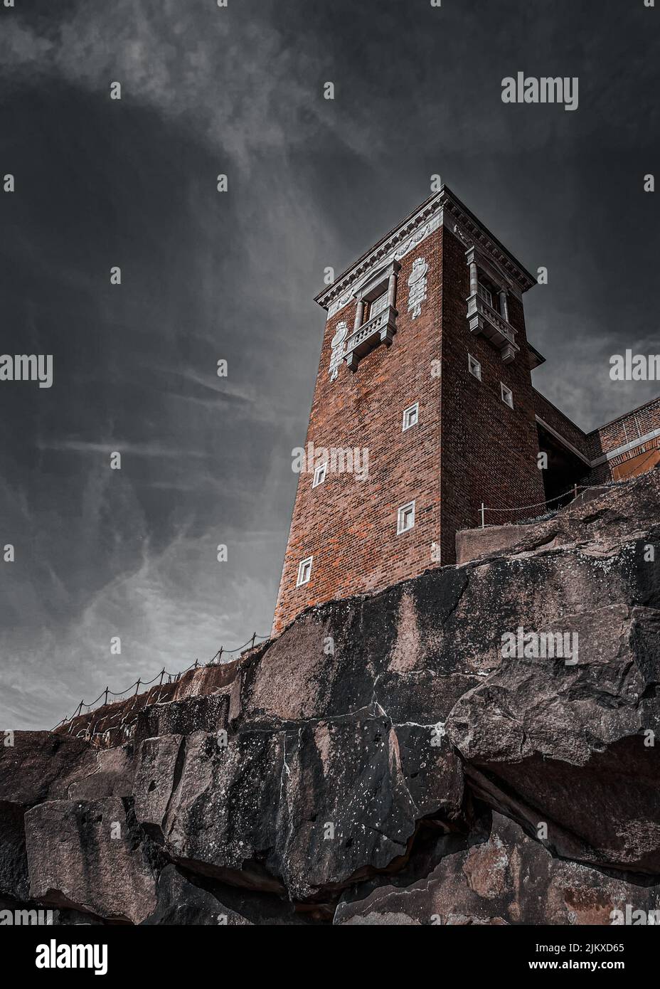 Una ripresa verticale ad angolo basso di una parte di un edificio sotto un cielo nuvoloso su una collina rocciosa Foto Stock