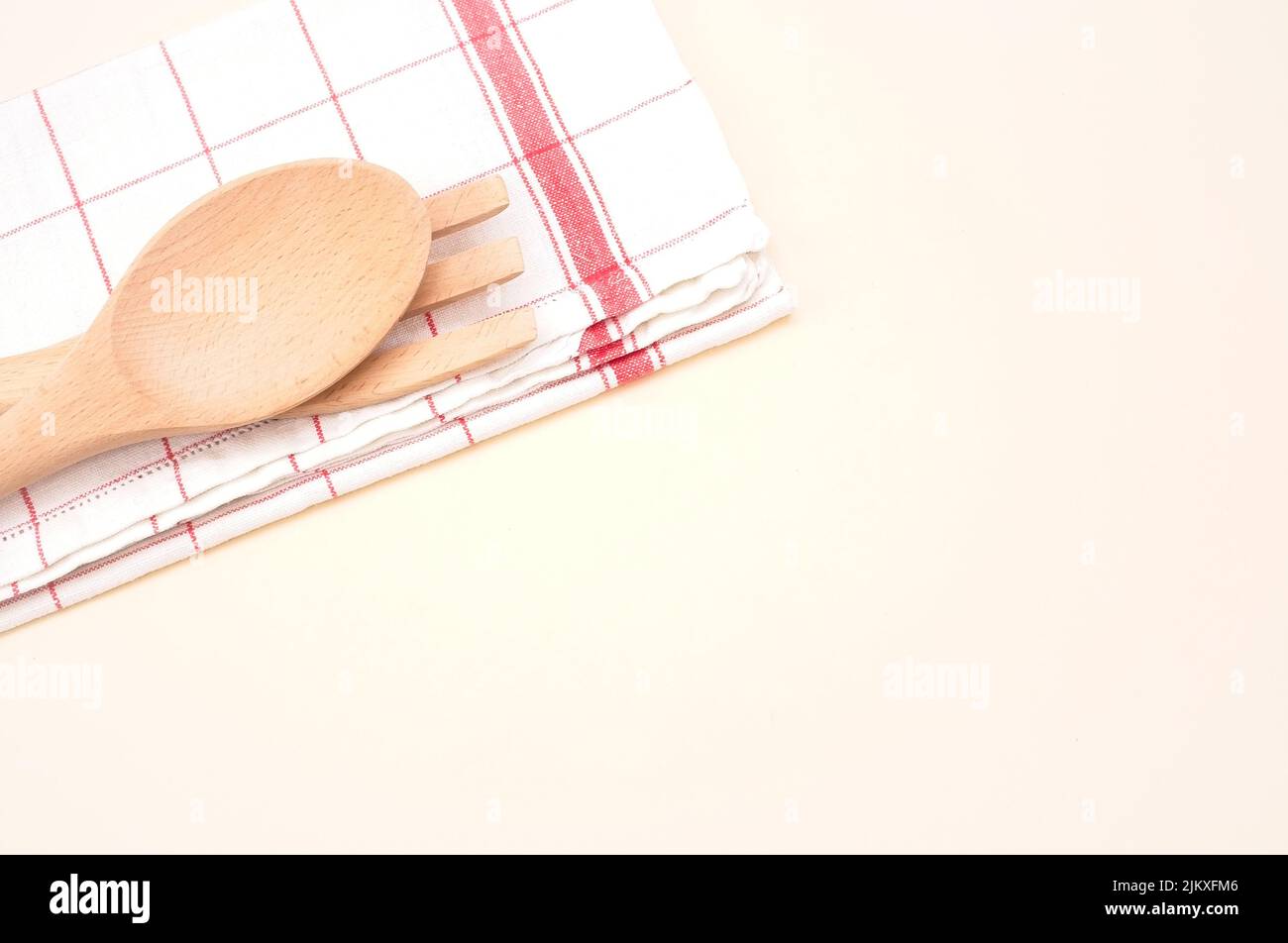 vista dall'alto del cucchiaio e della forchetta di legno con tovagliolo da tavolo su sfondo beige con spazio per il testo Foto Stock