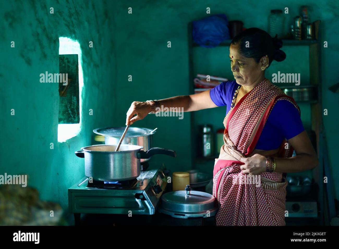 Un fuoco selettivo di una donna indiana che cucina in una cucina. Foto Stock